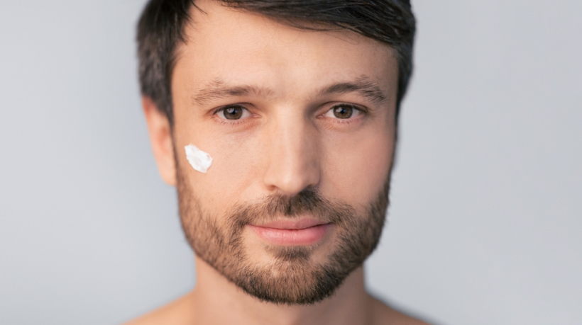 A,Man,With,A,Beard,Applies,Facial,Moisturizer,To,His